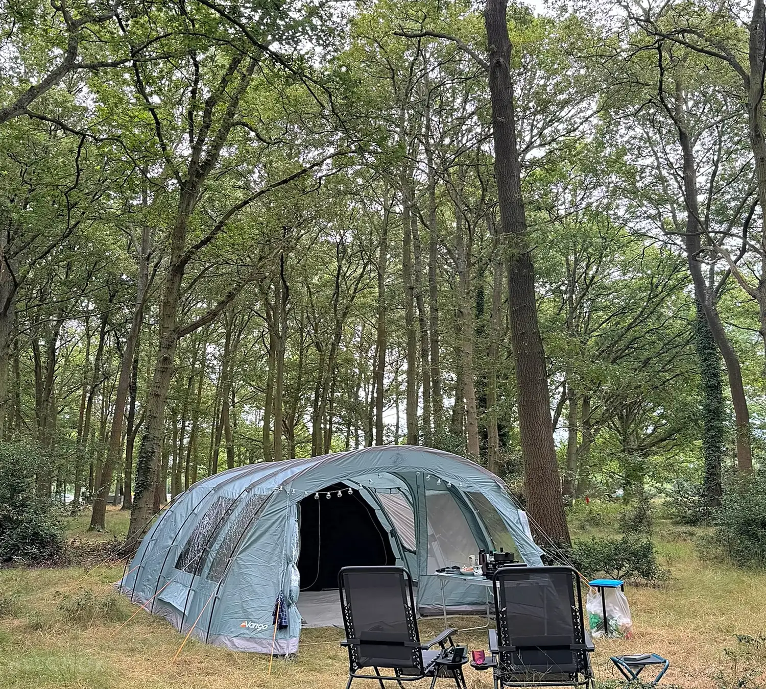 Camping chairs set out beside a tent in the sun